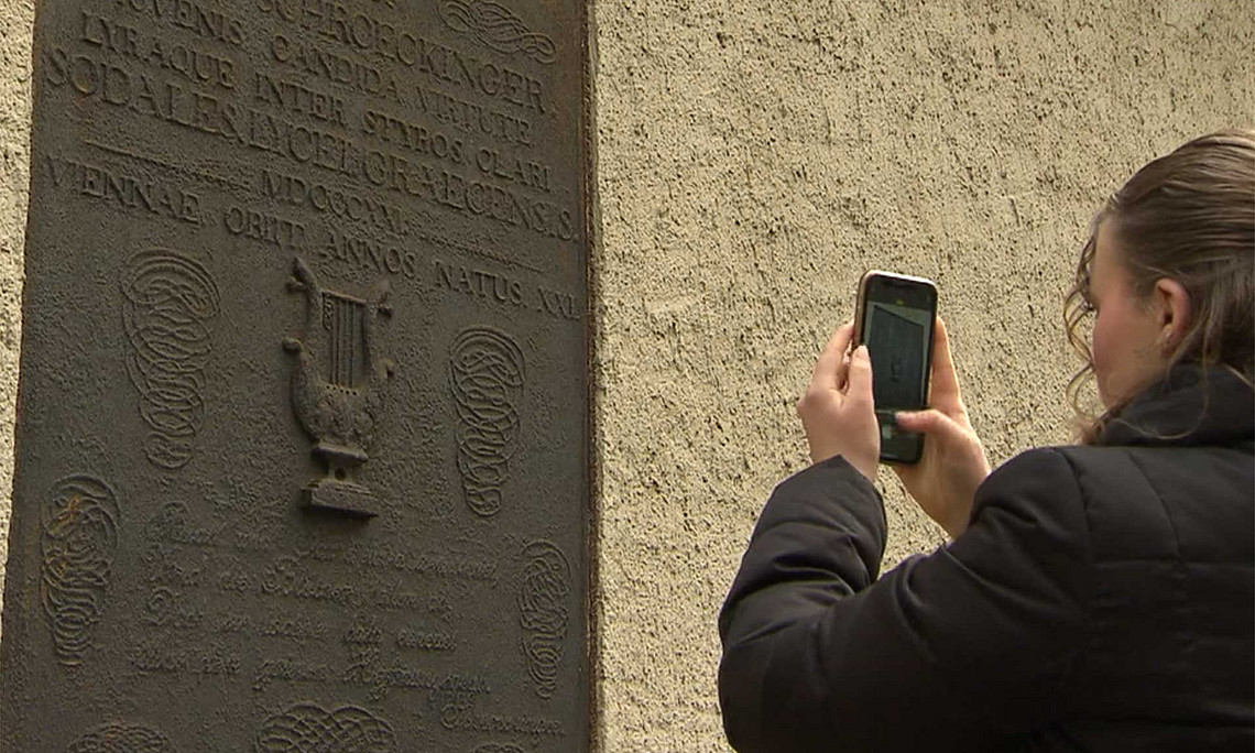 Schülerin fotografiert mit dem Handy eine Inschrift