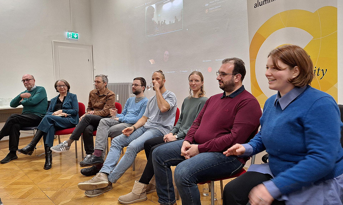 Eine Reihe von 8 Personen, die auf Stühlen sitzen