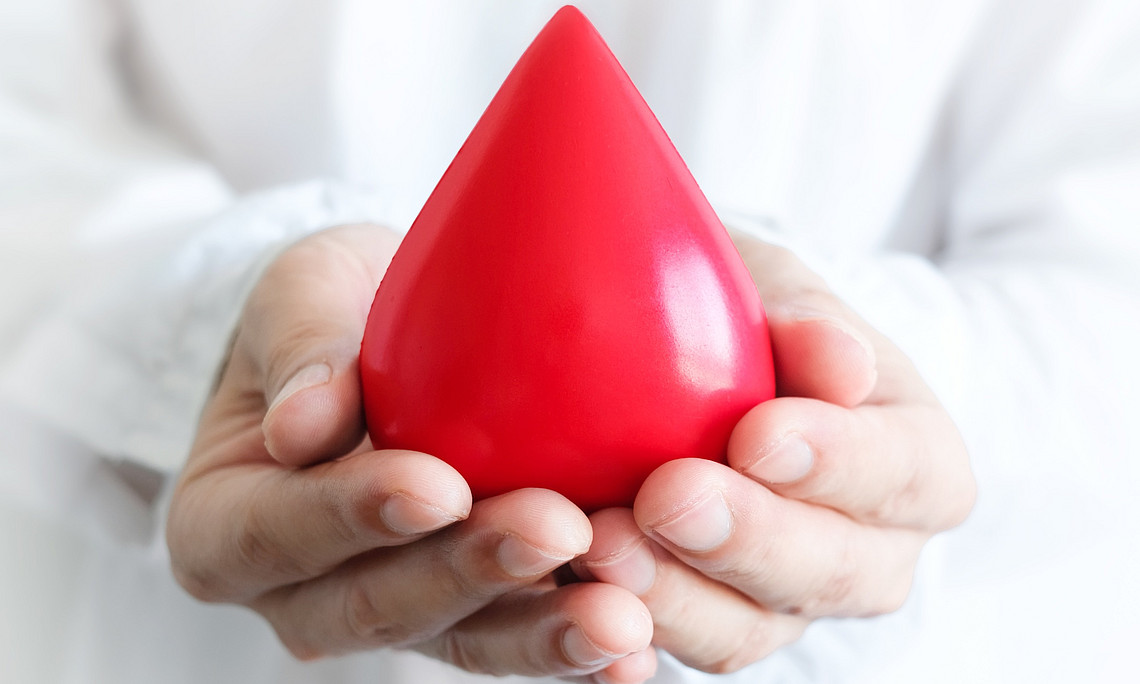 A man’s hand is holding a symbolic drop of blood