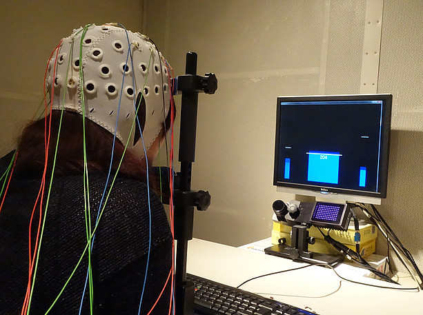 Eine Person mit aufgesetzter EEG Kappe übt Neurofeedback ©Silvia Kober