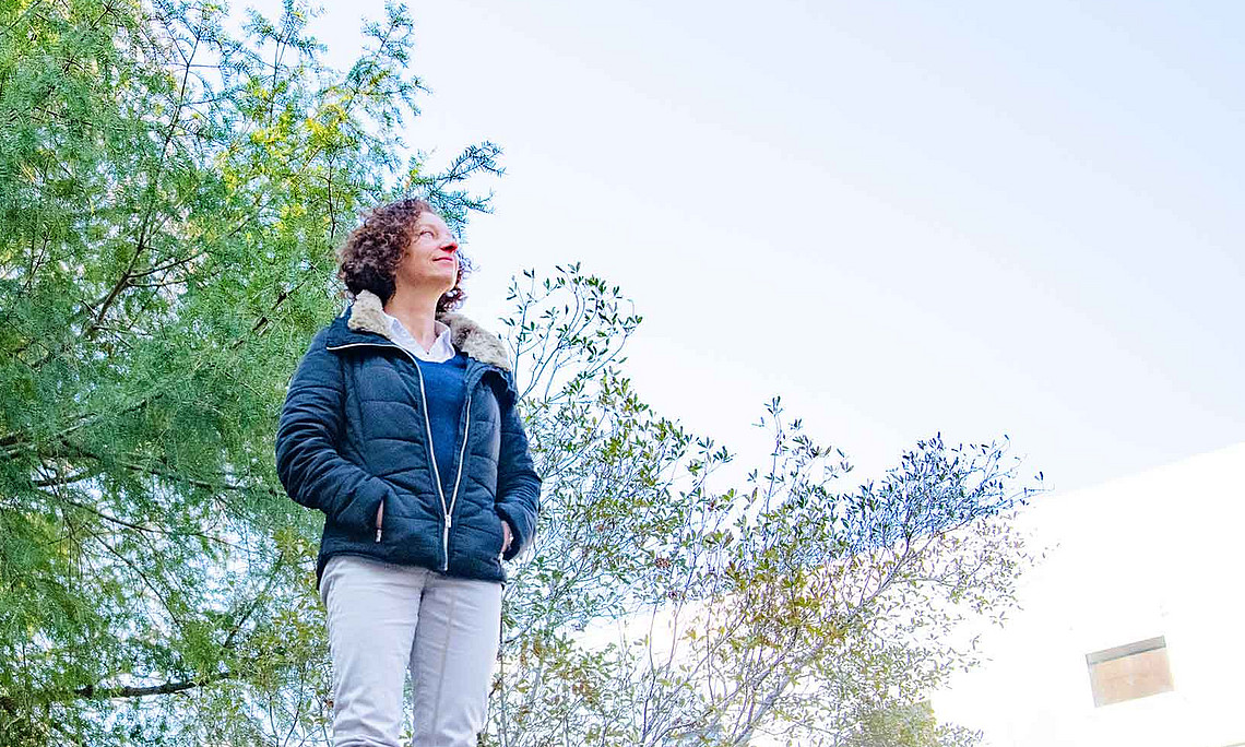 eine Frau steht auf einer Anhöhe und blickt in den Himmel
