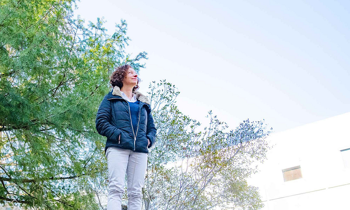 eine Frau steht auf einer Anhöhe und blickt in den Himmel