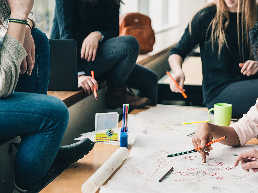 People sit around a table and design a poster that takes up the topic of Internationalization Abroad. ©Pixabay Lizenz/StockSnap