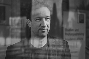 Portrait of philosopher Patrick Schuchter taken through a pane of glass with reflections