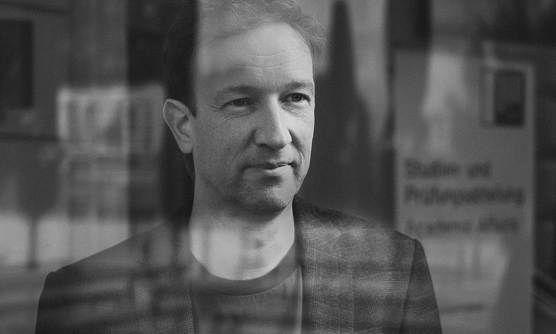 Portrait of philosopher Patrick Schuchter taken through a pane of glass with reflections