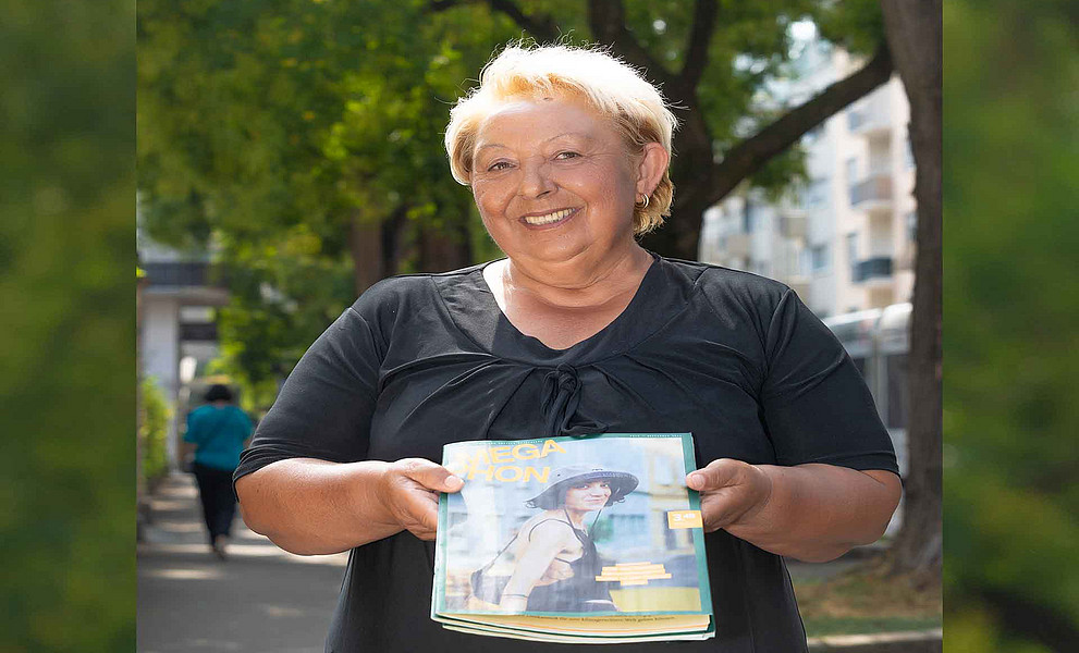 eine Frau hält ein Magazin in Richtung Kamera