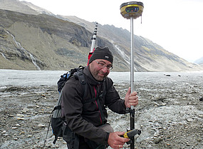 Andreas Kellerer-Pirklbauer with a measuring device at the edge of a glacier, scree on the ground