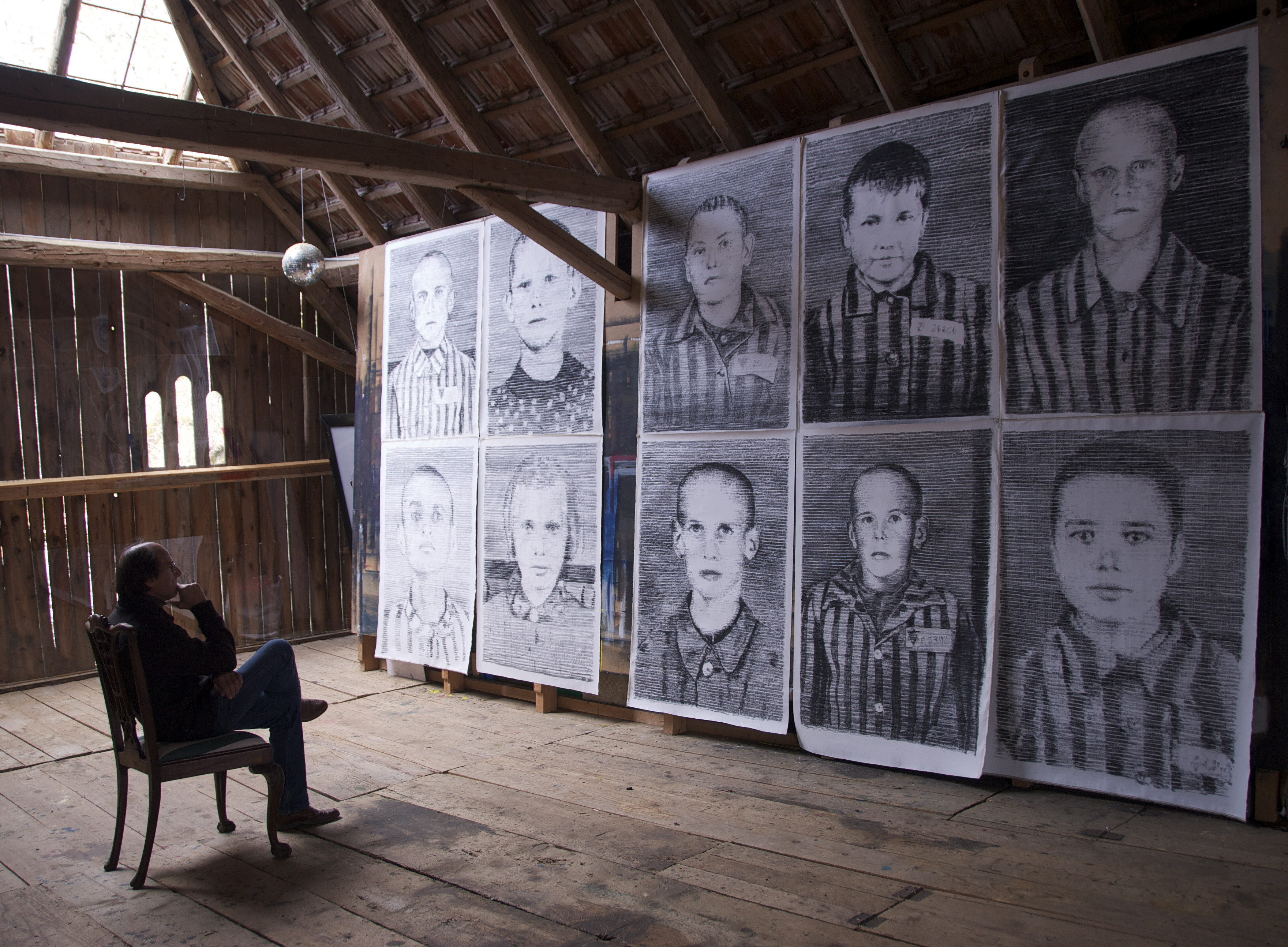 Der Maler sitzt in einem Sessel, gegenüber seine Bilder 