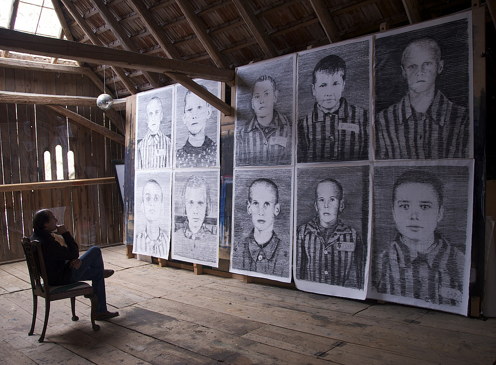 Manfred Bockelmann sitzt und schaut an seine Grafiken an. 