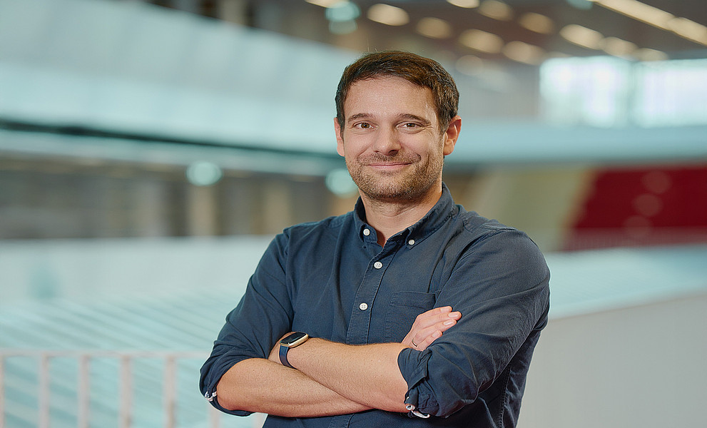 Paul Gragl mit verschränkten Armen in der Grazer Universitätsbibliothek