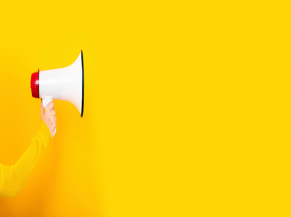 Announcement of the doctoral exam the SBESS, right hand in a yellow sweater holding a megaphone facing right against a yellow background. ©alesmunt - stock.adobe.com