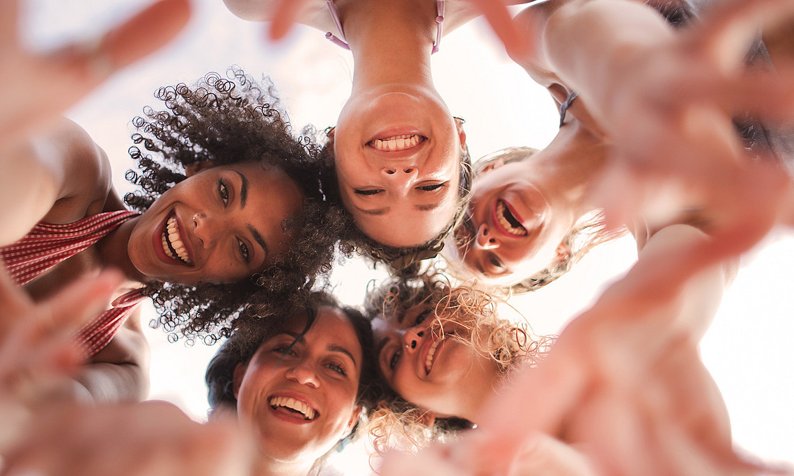 Fünf Frauen unterschiedlicher Herkunft, die sich umarmen, von unten fotografiert