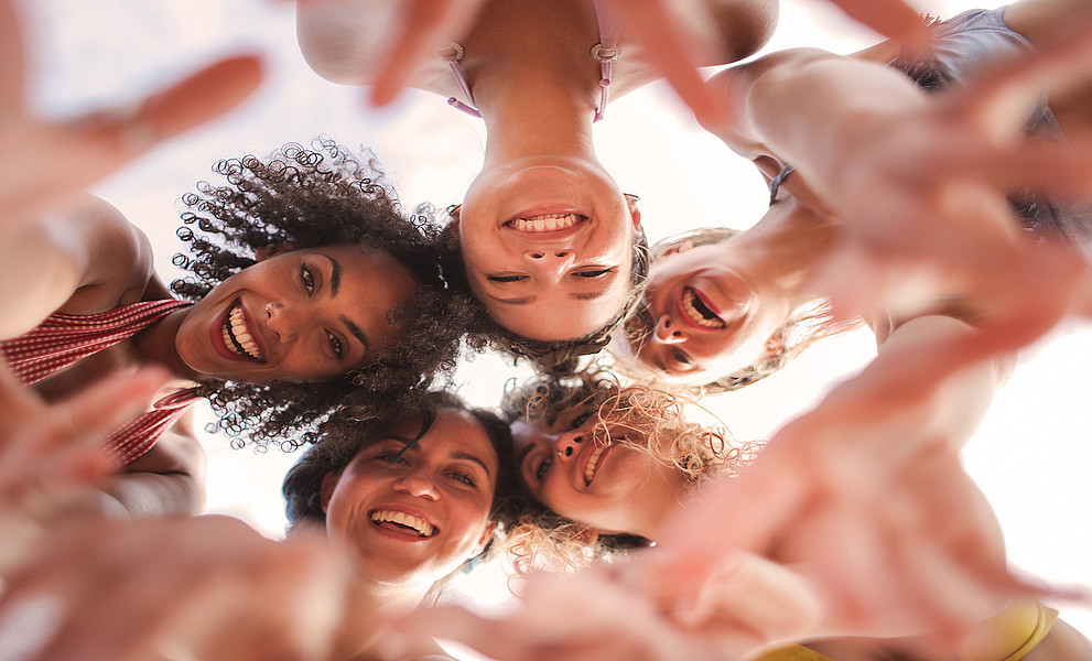 Fünf Frauen unterschiedlicher Herkunft, die sich umarmen, von unten fotografiert