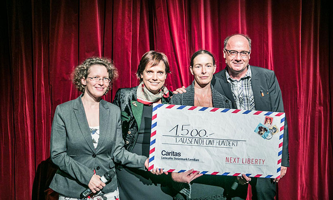 Julia Spiegl von unikid & unicare (l.), Renate Kasper (2.v.l.) und Next Liberty-Intendant Michael Schilhan überreichten den symbolischen Scheck an Silke Strasser, Leiterin der Lerncafés der Caritas Steiermark. Foto: Lupi Spuma. 