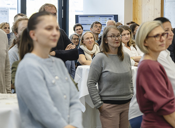 Gäste stehen an Stehtischen und hören einer Präsentation zu. ©@foto-gasser.at
