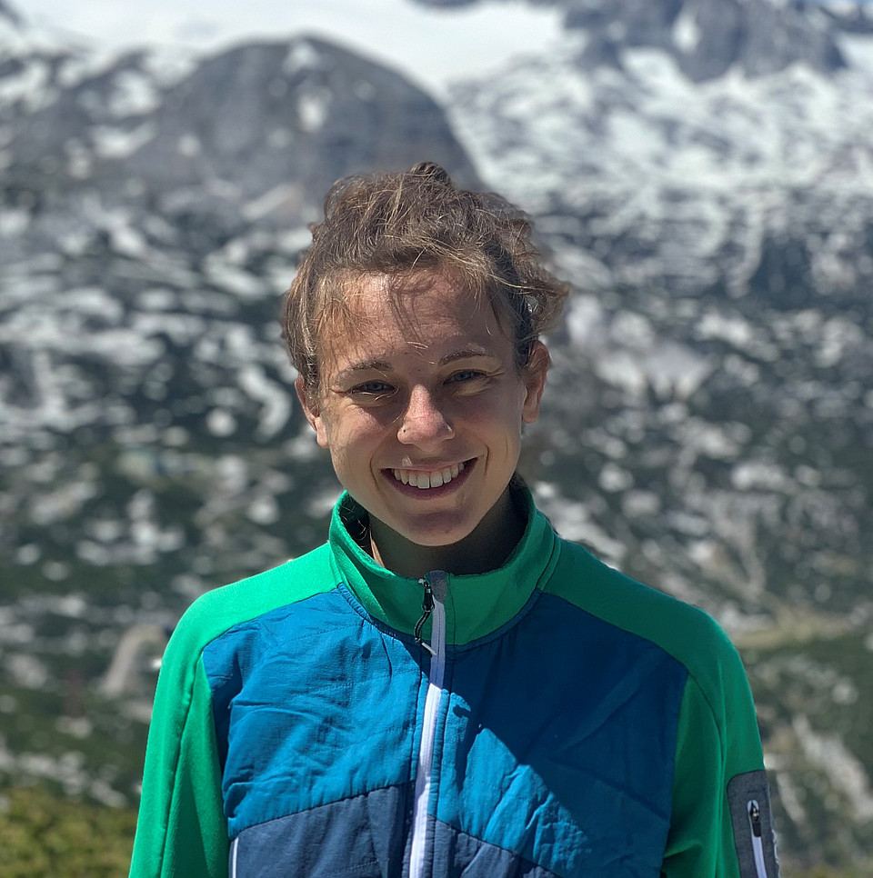 Fotografie von Katrin Kaltenegger, USW NAWI-Tech-Absolventin, in einer Berglandschaft, lächelnd, in Funktionskleidung.