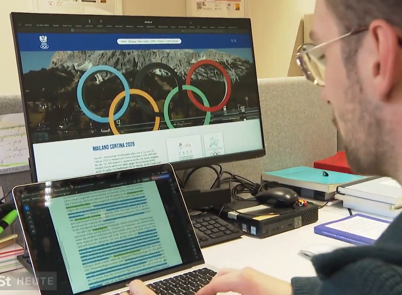 Wissenschaftler vor Bildschirm mit Olympia Symbol 