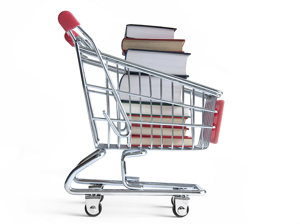 A representation of a small shopping cart filled with a stack of oversized books. ©Pixelbliss