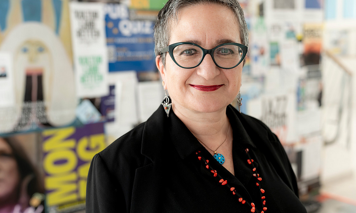 Portraitfoto von Sebnem Bahadir-Berzig vor einer bunten Posterwand im Wall-Zentrum der Universität Graz