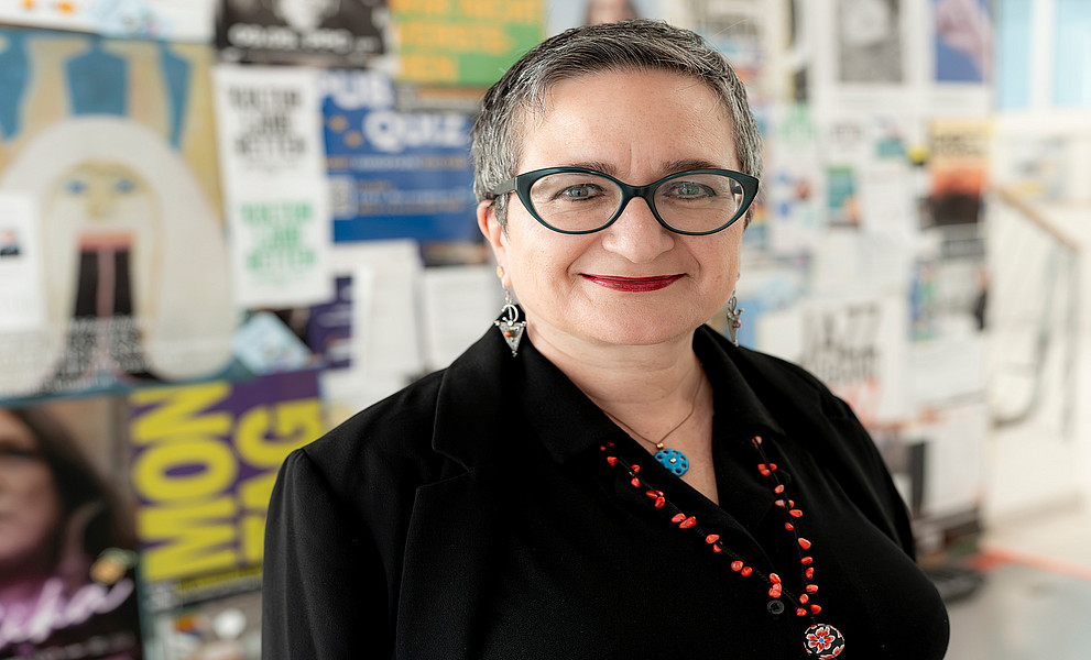 Portraitfoto von Sebnem Bahadir-Berzig vor einer bunten Posterwand im Wall-Zentrum der Universität Graz