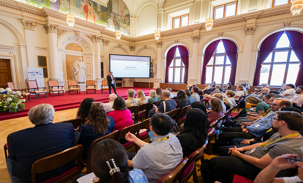 Ein Foto einer internationalen wissenschaftlichen Konferenz in einem Gebäude aus dem 19. Jahrhundert. Die Redner und Zuhörer hören während der Eröffnungszeremonie aufmerksam zu.