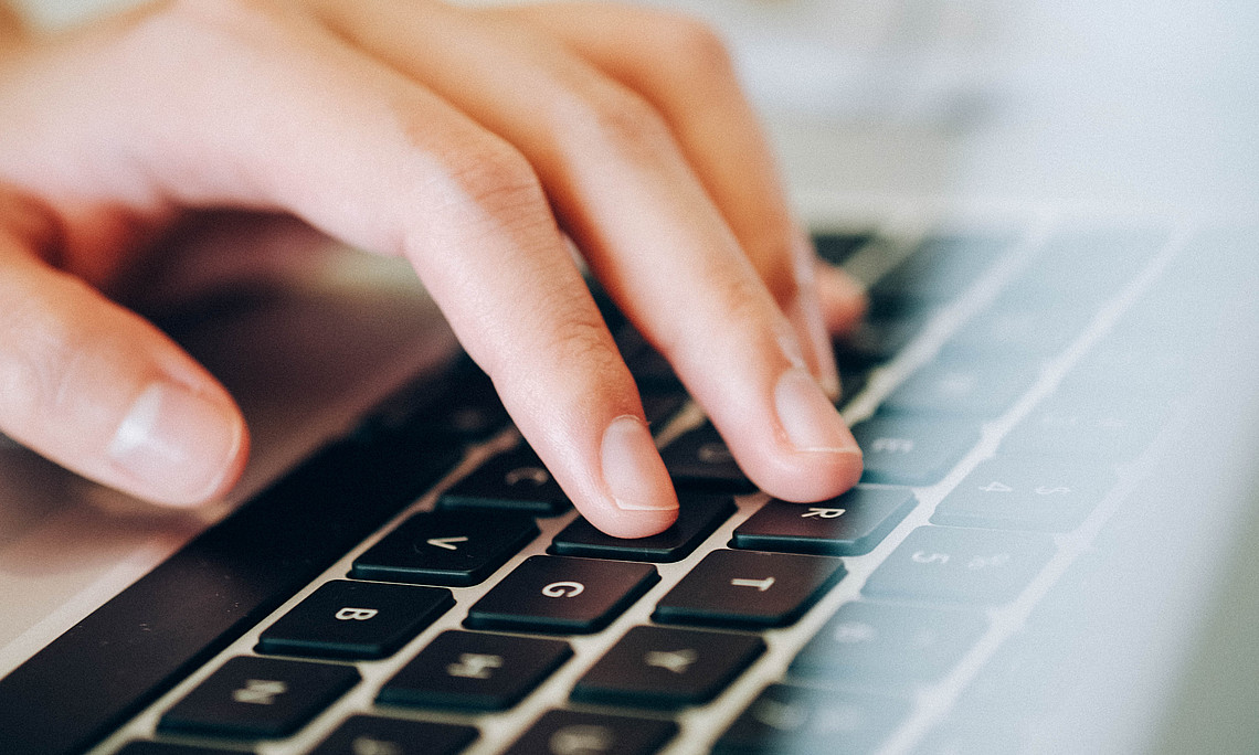 ein Hand, die auf der Tastatur tippt