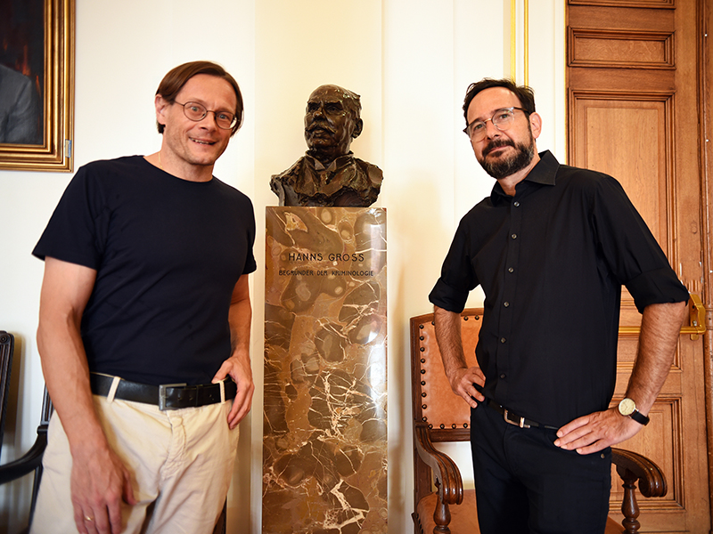 Christian Bachhiesl (links) und Gal Hertz vor der Hans-Gross-Büste in der Aula. Foto: Uni Graz/Schweiger 