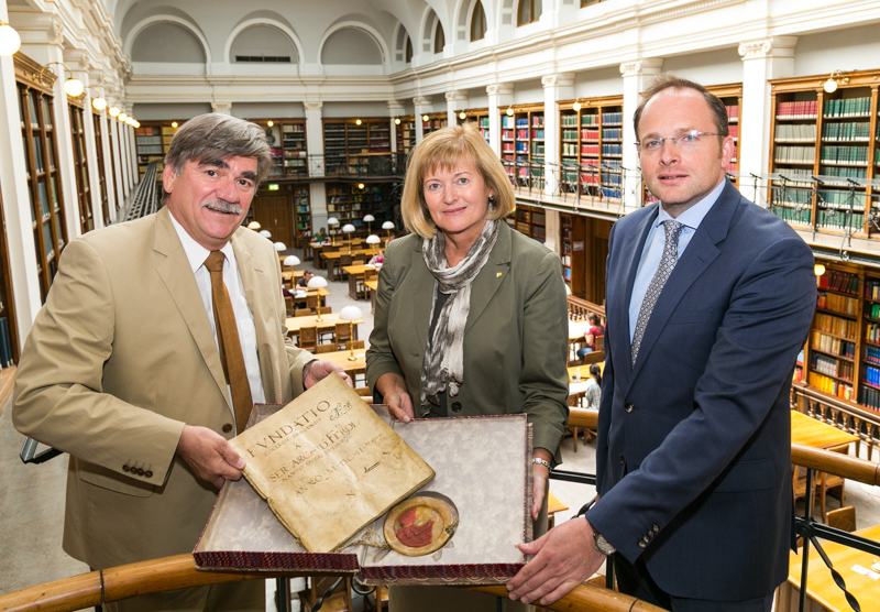 Noch ein Gruppenbild vorm großen Umbau: UB-Leiter Werner Schlacher, Rektorin Christa Neuper und Maximilian Pammer von der BIG (v.l.) mit einer Abschrift der Gründungsurkunde der Universität Graz aus dem Jahr 1602. Ab Herbst bleibt der Bibliotheks-Stand ©Fotoatelier Robert Frankl