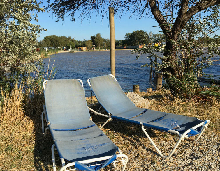 Foto mit zwei alten Liegestühlen vor einem See. Foto: Kugler 
