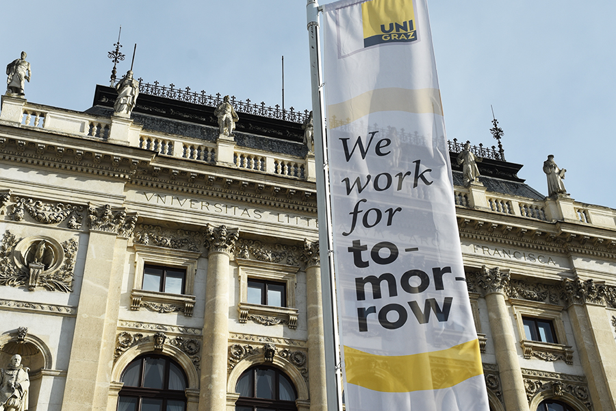 Hauptgebäude der Uni Graz mit Fahne "we work for tomorrow". Foto: Uni Graz/Tzivanopoulos 