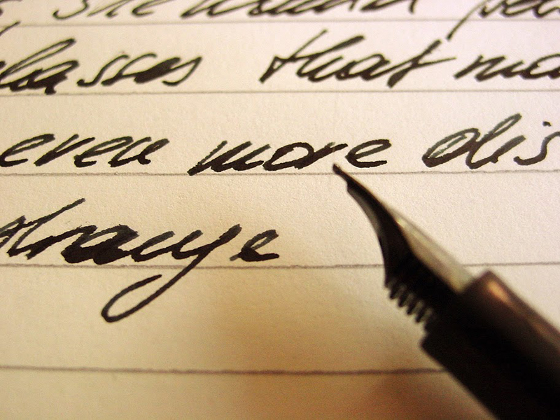 Feder vor Blatt mit Schrift 