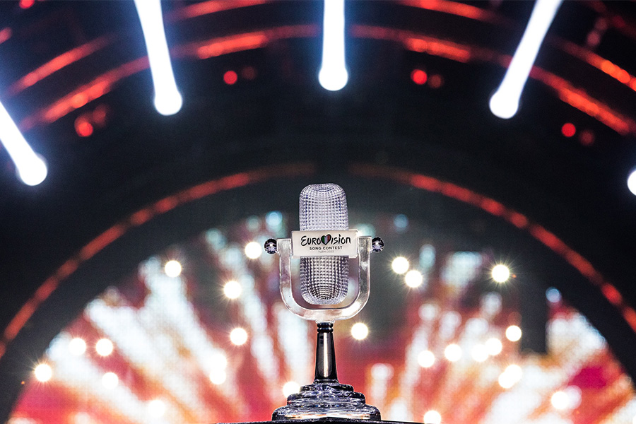 Die Trophäe des Eurovision Song Contest, ein gläsernes Mikrofon, im Hintergrund die Scheinwerfer der Bühne. 